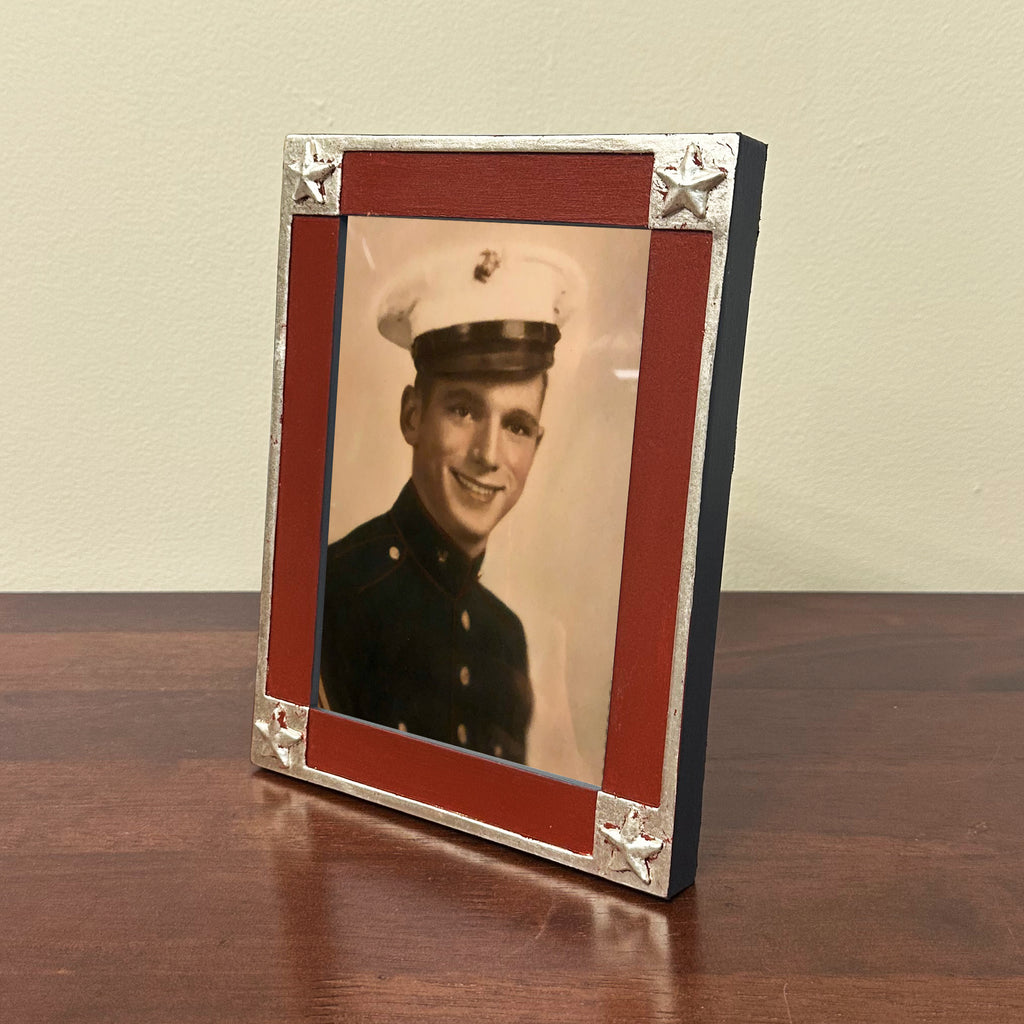 Vintage photo of a person in military uniform inside a decorative handmade frame on a wooden surface.